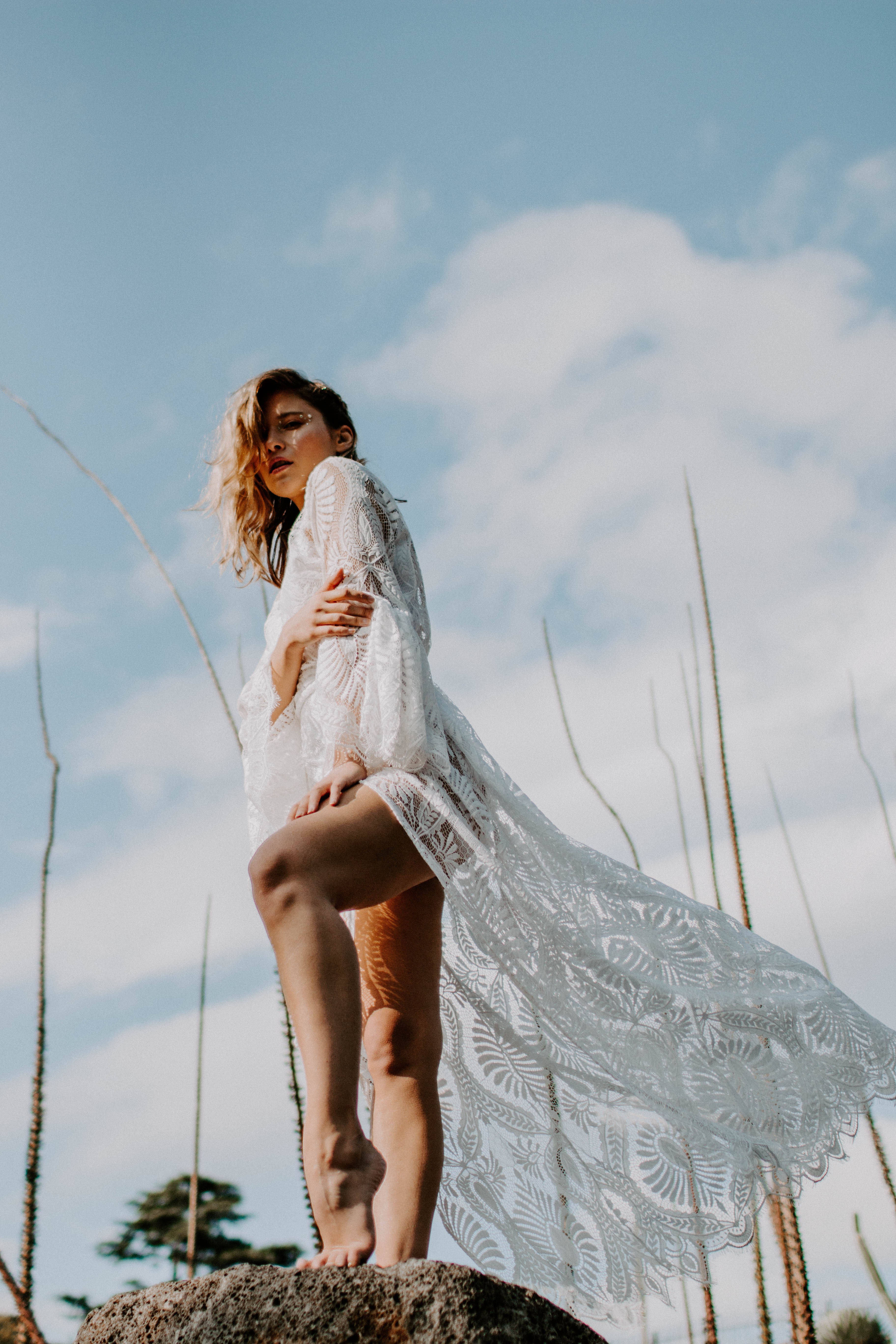 bride wearing bohemian lace dress standing on a rock 